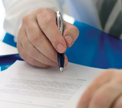 Hand holding a pen and writing on a piece of paper