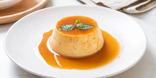 A decorated bowl of pannacotta style pudding with warm golden syrup speckled with cinnamon