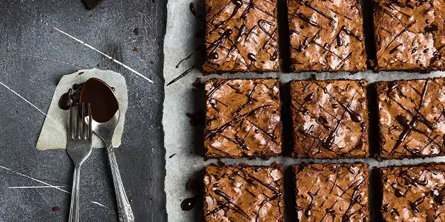 a tray of perfectly squared brownies with a baked top and drizzled with syrup