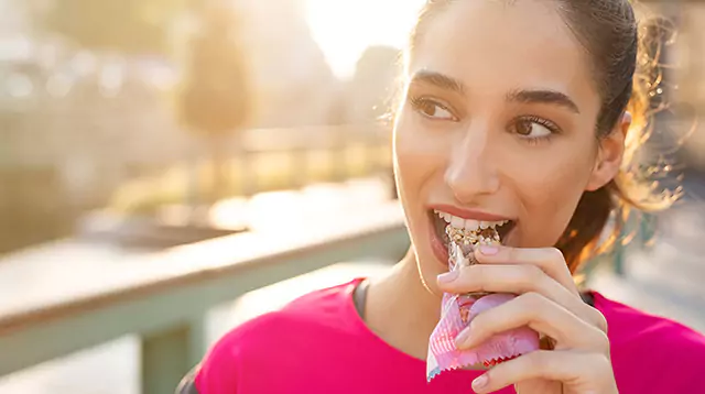 Close up shot a female eating a healthy snack bar