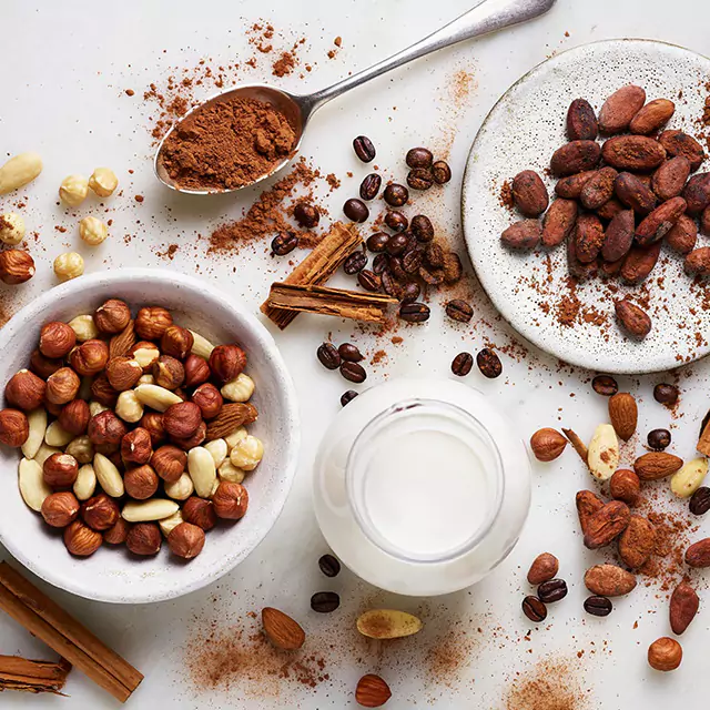 Close up shot of nut mix in white bowl with coffee beans covered in cocoa powder