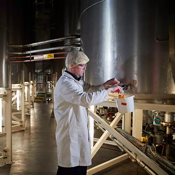 Britannia employee pouring liquid into a glass cup