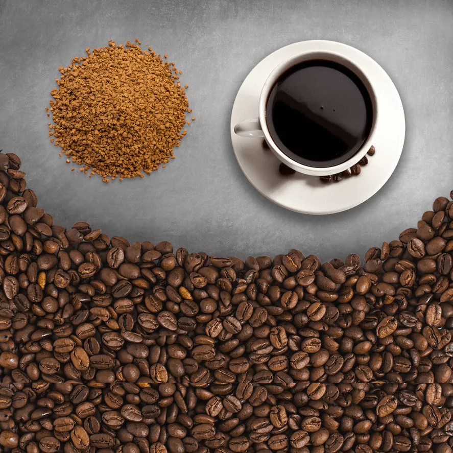 Roasted coffee beans with a pile of granulated coffee and a white cup of coffee