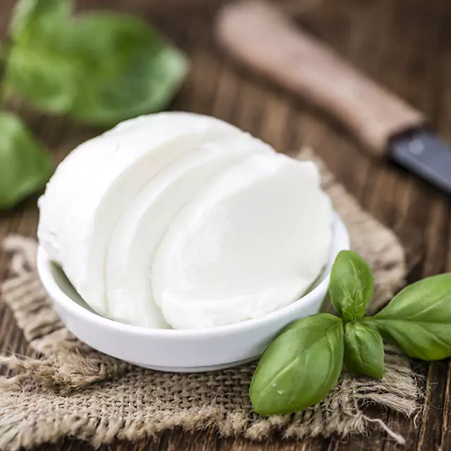 Close up shot of mozzarella cheese decorated with basil leaves