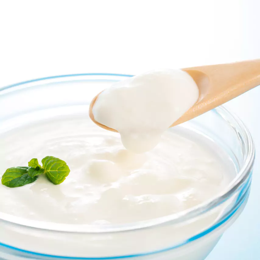 Close up shot of yogurt being scooped with a wooden spoon out of a bowl