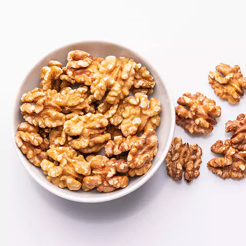 Close up shots of white bowl filled with walnuts pieces